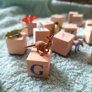Helle Holzwürfel auf einer Babydecke mit kleinen Gummitieren darauf.