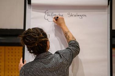 Eine Person schreibt Ideen auf ein Flipchart während eines Workshops.