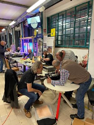 Eine Kleingruppe hilft beim Repair Café zusammen, um kaputte Teile wieder in Ordnung zu bringen.